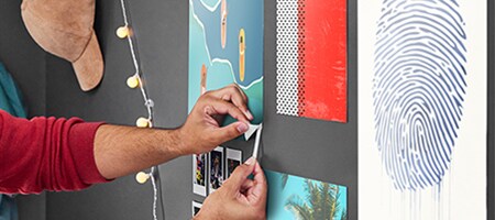 A student stretches down on a Command™ Poster Strip to remove a poster from their uni room wall
