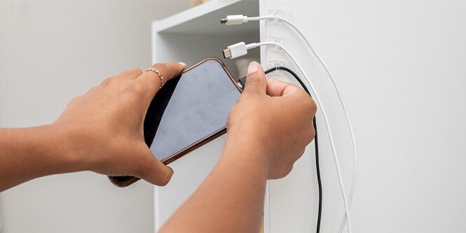 Command™ Clear Clips are used on a bedside cabinet to keep charging cables neat and tidy
